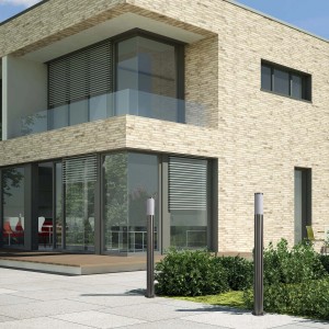 Dwie nowoczesne lampy zewnętrzne t.b.t. ze stali nierdzewnej przed domem. Lampy dekoracyjne do ogrodu i na patio.