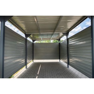 Szary metalowy garaż t.b.t. ze ścianami bocznymi i dachem na kostce brukowej.