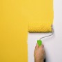 Ręka maluje ścianę żółtym wałkiem Vestanroller, wałek malarski 18 cm do gładkich powierzchni.