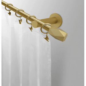 Złoty karnisz z geometrycznym zakończeniem i kółkami do zasłon.