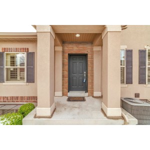 Fasada domu z ciemnymi drzwiami wejściowymi i dekoracyjnymi cegłami klinkierowymi w strefie wejściowej.