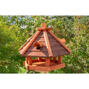 Drewniany karmnik dla ptaków z dachem i stołem do karmienia w ogrodzie.