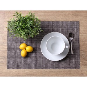 Podkładka na drewnianym stole z filiżanką, spodkiem, łyżką, cytryną i rośliną.