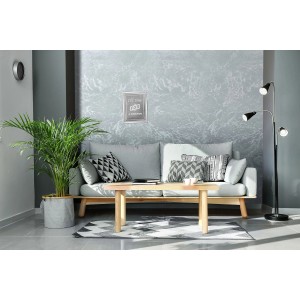 Salon z szarą farbą efektową na ścianie, sofa, stół i roślina doniczkowa.