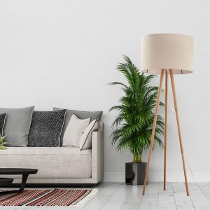 Lampa podłogowa t.b.t. z drewna i abażurem obok sofy i rośliny.