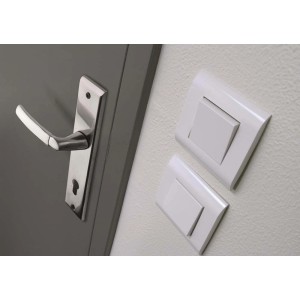 Drzwi z klamką t.b.t. ze stali nierdzewnej i białymi włącznikami światła na ścianie.