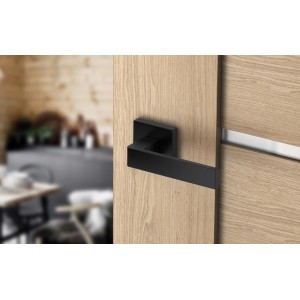 Czarna klamka do drzwi na drewnianych drzwiach. Okucia do drzwi wewnętrznych.