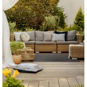 Szary dywan z krótkim włosiem t.b.t. na drewnianym tarasie z meblami rattanowymi w ogrodzie.