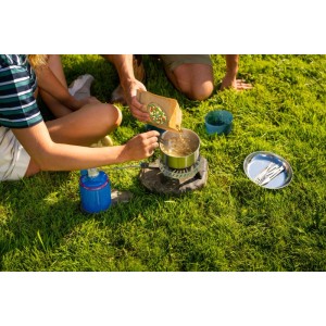 Ludzie gotują na zewnątrz na kuchence gazowej Campingaz. Niebieska kuchenka kempingowa z garnkiem na zielonej trawie. Idealna na trekking.