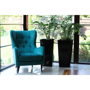 Czarna donica Orbis Finezja (75x40x40cm) obok fotela, do wewnątrz i na zewnątrz.