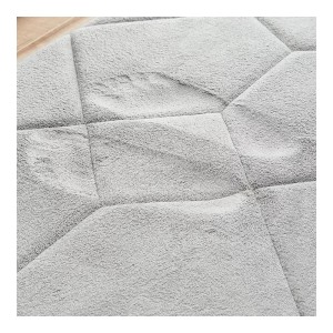 Zbliżenie na szarą, pikowaną matę łazienkową.