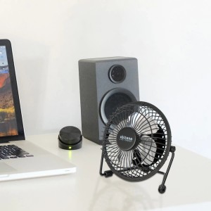Czarny wentylator biurkowy t.b.t. obok laptopa i głośnika.