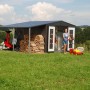 Metalowy domek narzędziowy Biohort Europa w kolorze ciemnoszary metalik z akcesoriami i użytkownikiem w ogrodzie.