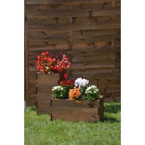Drewniana skrzynka na rośliny przed drewnianym płotem obsadzona kolorowymi kwiatami.
