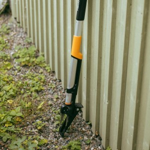 Ergonomiczny wyrywacz do chwastów Fiskars, pomarańczowo-czarny, z czterema pazurami do usuwania chwastów w ogrodzie.