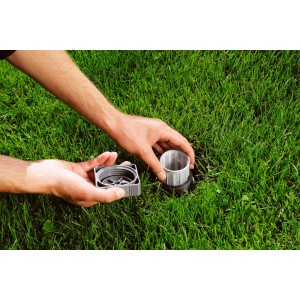 Filtr centralny Gardena do systemów zraszających w trawniku, z rękami podczas instalacji.
