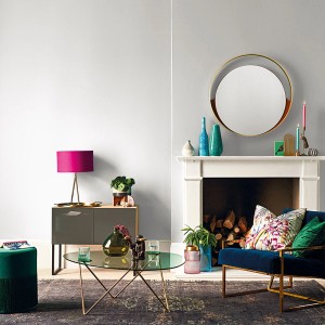 Salon z szarą pomalowaną ścianą, ozdobiony meblami i akcesoriami w różnych kolorach.