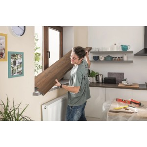 Mężczyzna montuje parapet t.b.t. w kuchni. Dekor drewna.