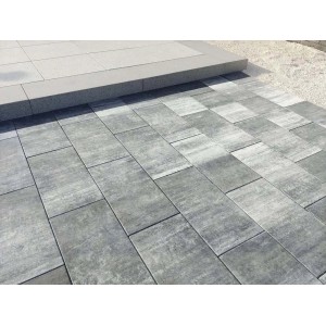 Szare płyty tarasowe i chodnikowe t.b.t. ułożone na zewnątrz.