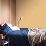 Sypialnia z żółtą farbą na ścianie. Kolorowe farby do ścian.
