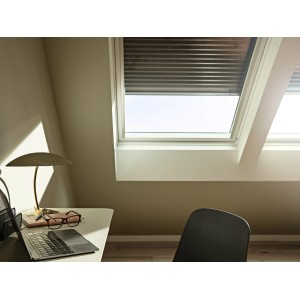 Roleta solarna Velux SSL CK02, ciemnoszara, częściowo otwarta na oknie dachowym na poddaszu.