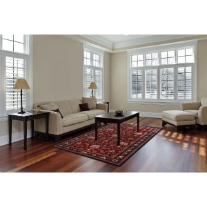 Czerwony wzorzysty dywan w salonie z sofą i stołem. Dywan z krótkim włosiem.