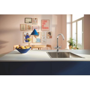 Zestaw baterii kuchennej Grohe Blue Pure Start Curve z filtrem z węglem aktywnym w kolorze srebrnym przed zlewem.