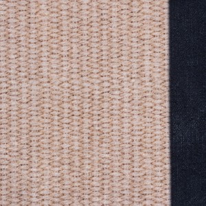 Zbliżenie dywanu z krótkim włosiem t.b.t. z beżowym wzorem i ciemnym obramowaniem.