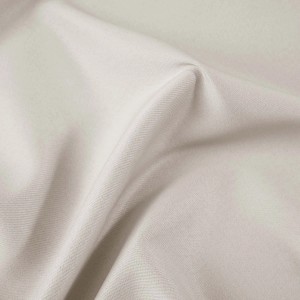 Zbliżenie beżowej tkaniny zasłonowej.