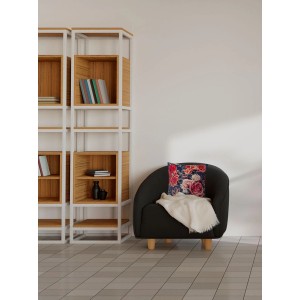 Dekoracyjna poduszka t.b.t. na fotelu z kocem, obok półki.