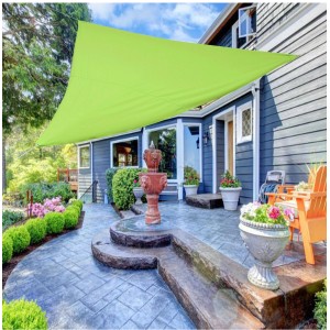 Zielona markiza t.b.t. zapewnia cień na patio z fontanną i meblami ogrodowymi.