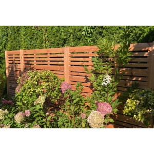 Drewniane panele ogrodzeniowe t.b.t. w ogrodzie z roślinami.