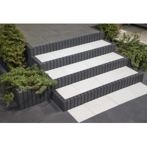 Schody z szarym obrzeżem palisadowym i białymi stopniami, otoczone zielenią.