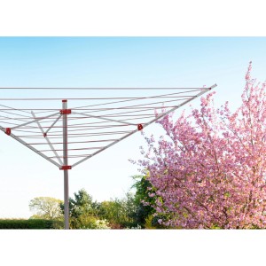 Obrotowa suszarka do prania t.b.t. w ogrodzie z kwitnącym drzewem. Praktyczne suszenie prania na zewnątrz.