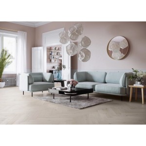 Jasny salon z drewnianą podłogą t.b.t., pastelową sofą i fotelem.