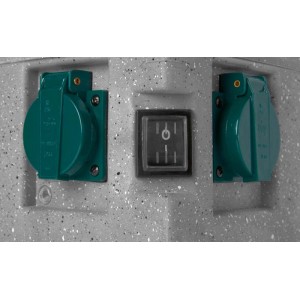 Zbliżenie: Dwa zielone gniazdka elektryczne t.b.t. i włącznik na szarej powierzchni.