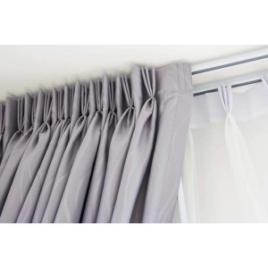 Szara zasłona z plisami na podwójnym karniszu.