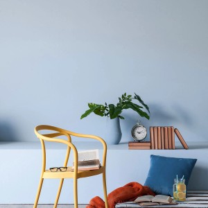 Aranżacja wnętrza z farbą do ścian t.b.t. w jasnoniebieskim kolorze, żółtym krzesłem i elementami dekoracyjnymi.