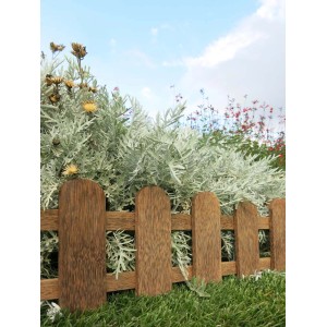 Drewniana obrzeże ogrodowe, brązowa palisada przed zielonymi roślinami i błękitnym niebem.