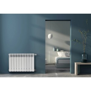 Biały grzejnik t.b.t. na niebieskiej ścianie w nowoczesnej sypialni.