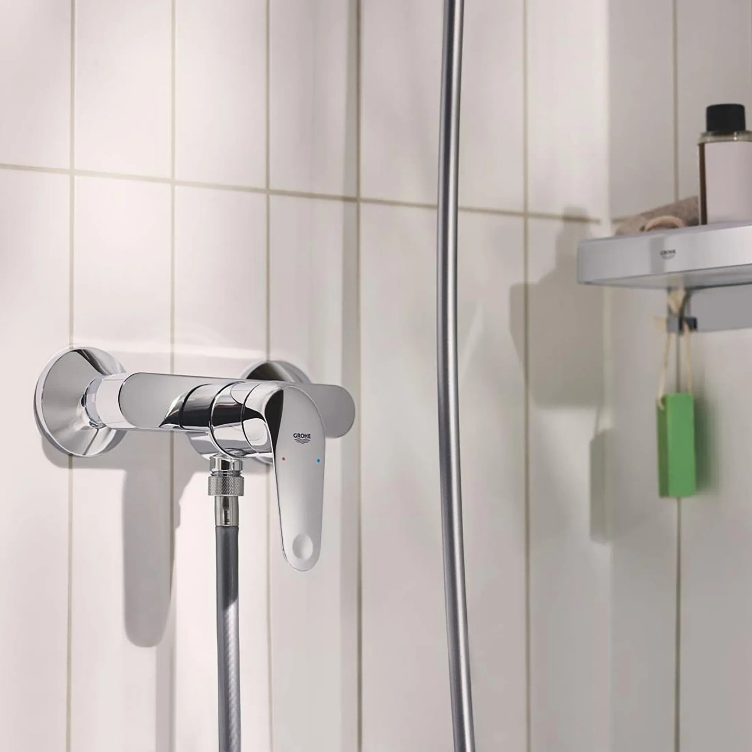 Błyszcząca chromowana bateria prysznicowa Grohe Swift z jednym uchwytem, zamontowana na białej ścianie.