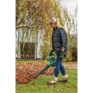 Kobieta używa odkurzacza ogrodowego Bosch UniversalGarden Tidy 2300 do zbierania liści.