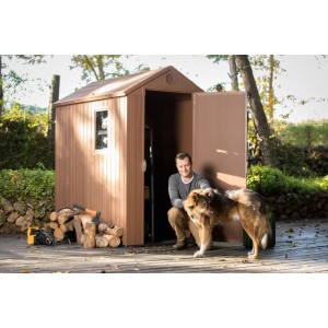 Brązowy plastikowy domek narzędziowy z mężczyzną i psem przed nim. Idealny do przechowywania w ogrodzie.