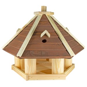 Drewniany karmnik dla ptaków z brązowym dachem i miejscem do karmienia w ogrodzie.