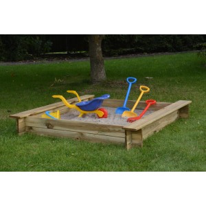 Drewniana piaskownica z zabawkami, takimi jak łopaty i taczka w ogrodzie.