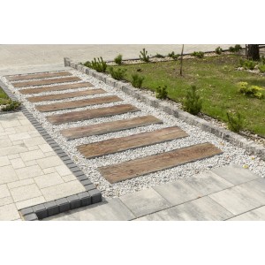 Drewniane płyty tarasowe jako ścieżka ogrodowa między żwirem a kostką brukową.