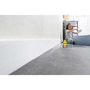 Biała listwa przypodłogowa t.b.t. w łazience z bawiącym się dzieckiem.