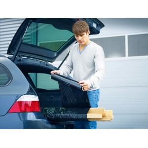 Mężczyzna pakuje drewno czarną folią stretch LUX w bagażniku samochodu.