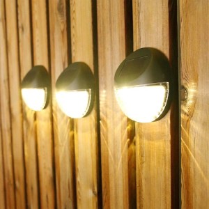 Trzy okrągłe solarne lampy ścienne na drewnianej ścianie. Kinkiety solarne do ogrodu i na patio.