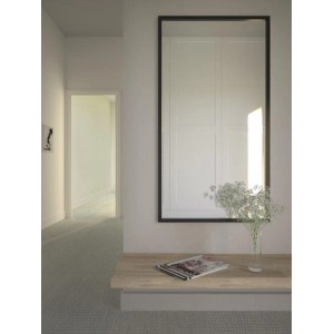 Prostokątne lustro t.b.t. z czarną ramą na ścianie nad stołem.